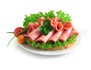 sliced sausage with herbs and vegetables on a white plate.