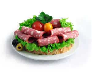 sliced sausage with herbs and vegetables on a white plate.