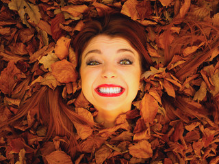 Portrait of young woman in autumn leaves.