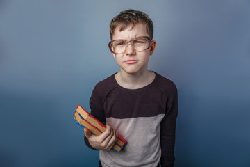 European-looking boy of ten years  in  glasses reading  a book o