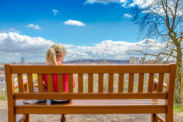 junge Frau sitzt auf einer Holzbank mit Ausblick himmel