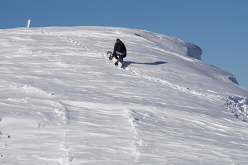 Snowboarder climbing a snowy mountain