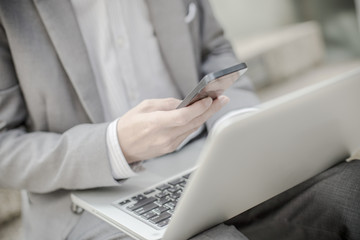 Businessman using laptop pc and mobile phone. He is sitting on a