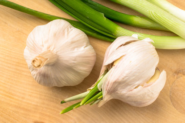 Two garlic bulbs next to the green onions