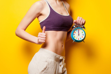 Woman showing her abs with alarm clock