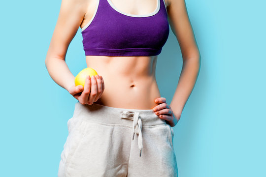Woman showing her abs with apple after weight loss