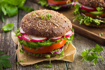 Healthy fast food. Vegan rye burger with fresh vegetables - obrazy, fototapety, plakaty