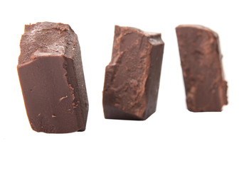 Dark brown chocolate pieces over white background