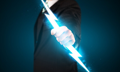 Business man holding glowing lightning bolt in his hands