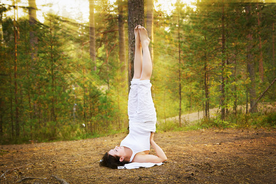 Young Woman In Yoga Shoulder Stand In Forest