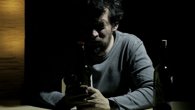 man with drinking problems at home with bottle of wine