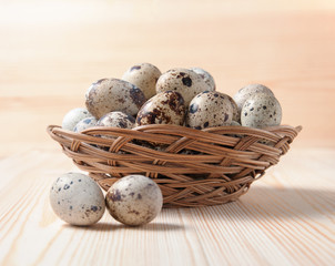 Quail eggs in a wicker bowl standing on wooden boards