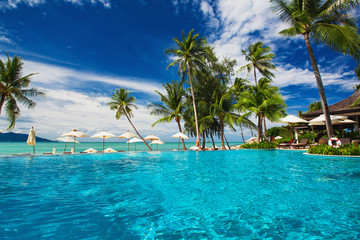 Infinity swimming pool on the beach with palm trees