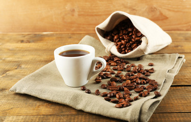 Cup of coffee with beans on rustic wooden background