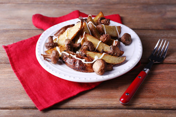 Baked potatoes with mushrooms and sauce on plate on wooden