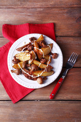 Baked potatoes with mushrooms and sauce on plate on wooden