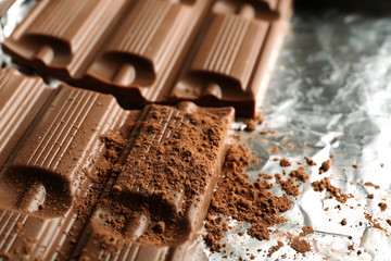 Bar of chocolate with cocoa on foil, closeup