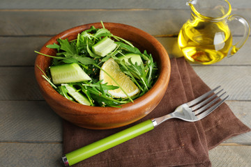 Bowl of green salad and sliced lemon on wooden background