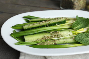 Green salad with cucumber and wild leek on wooden table,