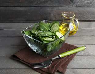 Glass bowl of green salad with cucumber and spinach