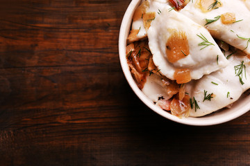 Tasty dumplings with fried onion in brown bowl,