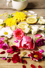Cup of herbal tea with beautiful flowers, on wooden background