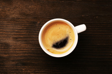 Cup of coffee on wooden table, top view