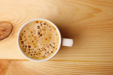 Cup of coffee on wooden table, top view
