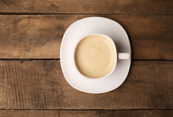 Cup of coffee on wooden table, top view