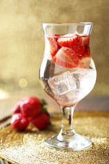 Glass of freshness water with strawberries, on bright