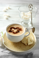 Cup of latte coffee art on wooden table, on light background