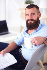 Young man sitting with laptop and a tea cup at home