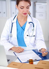 Fototapeta na wymiar Beautiful young smiling female doctor sitting at the desk and