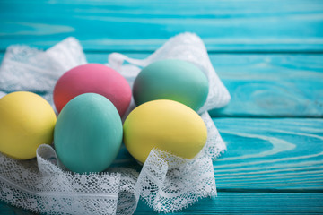 easter colored eggs with lace ribbon on blue wooden background