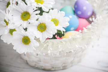 Fototapeta na wymiar easter present basket with white flowers and colored eggs