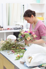 Masterclass of smiling florist at work with bunch of flowers