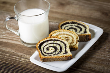 Glass of milk with poppy seed cakes on wooden background