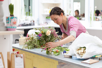 Masterclass of smiling florist at work with bunch of flowers