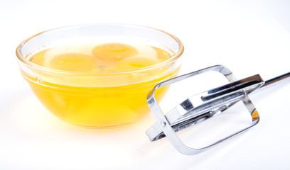 Fresh eggs in white bowl and stainless steel auto beater on whit