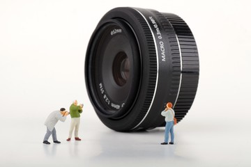 miniature di fotografi davanti ad un obiettivo fotografico