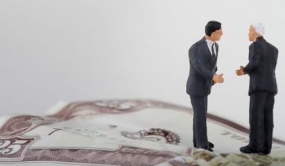 miniature di uomini d'affari che trattano su una banconota