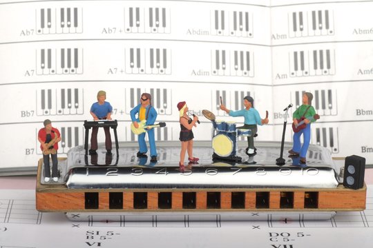 gruppo rock in miniatura mentre suona su un'armonica a bocca
