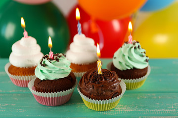 Delicious birthday cupcakes on table on bright background