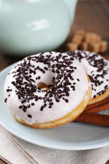 Delicious donuts with icing on plate on table close up