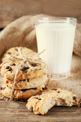 Tasty cookies and glass of milk on rustic wooden background