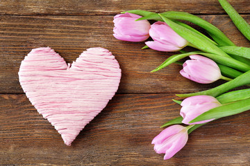 Obraz na płótnie Canvas Beautiful pink tulips with decorative heart on wooden