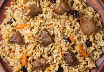 Pilaf with large pieces of fried meat, spicy rice, carrot and