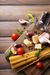 Raw pasta with cheese and vegetables on wooden background