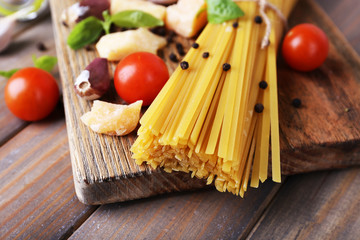 Raw pasta with cheese and vegetables on table close up