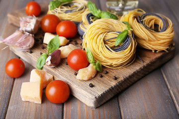 Raw pasta with cheese and vegetables on wooden background